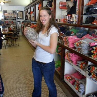 A woman stands in a store and holds a crystal football trophy.